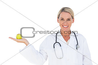 Happy doctor holding apple and looking at camera