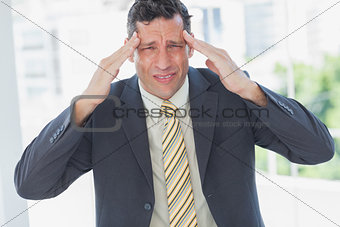 Businessman rubbing his temples and frowning at camera