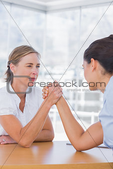 Rival businesswomen having an arm wrestle