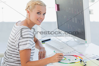 Cheerful photo editor pointing at a colour wheel