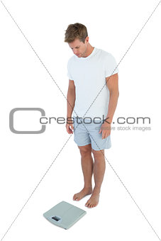 Athletic man looking at a weighing scale