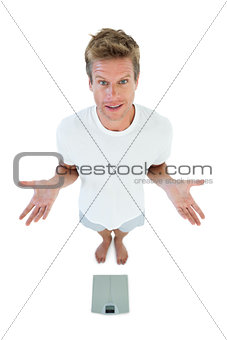 Man gesturing in front of a weighing scale