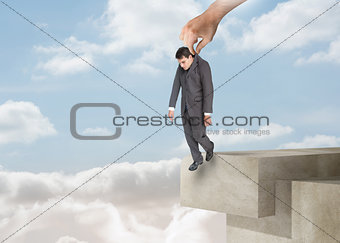 Giant hand dropping off a businessman over the clouds