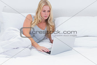 Woman lying on her bed using a laptop
