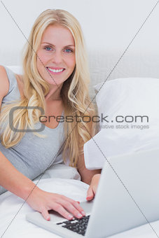Woman using her laptop on her bed