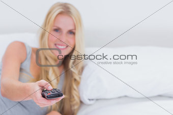 Woman pointing the remote control at the camera