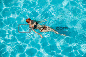 Young redhead woman in swimming pool 