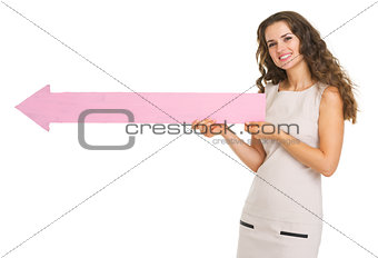 Smiling young woman pointing on copy space with arrow