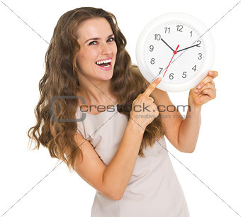 Smiling young woman pointing on clock
