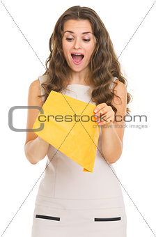 Surprised young woman opening letter