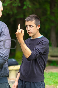 Boy showing middle finger to adult