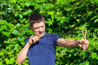 Boy with a slingshot near the bush