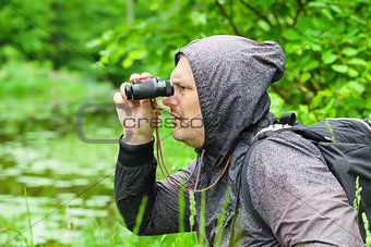 Man with binoculars watching birds at the lake