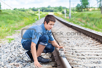 Boy puts stones on railway tracks