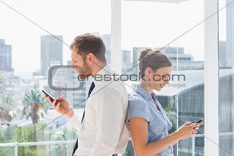 Business team standing back to back and texting