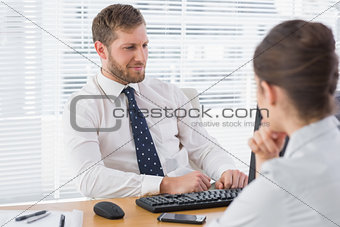 Businessman meeting with a co worker at his desk