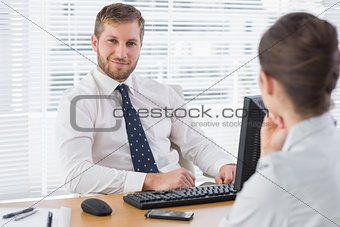 Businessman sitting with a co worker at his desk