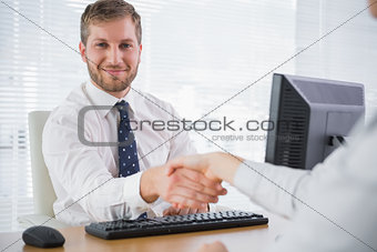 Smiling businessman shaking hands with a co worker and looking at camera