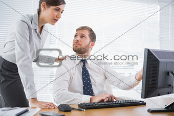 Businessman showing his co worker something on computer