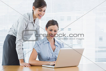Businesswoman looking at co workers laptop