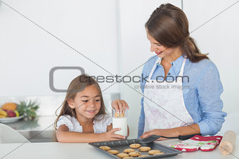 Little girl dunking a cookie into a glass of milk