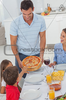 Handsome man bringing a pizza to his family