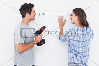 Cheerful man and his wife doing home improvements together