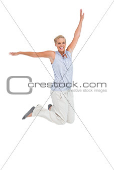 Blonde woman jumping with hands up in air