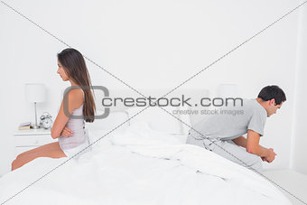 Couple sulking each other sitting on bed