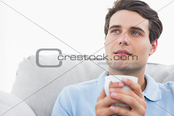 Man holding a cup of coffee sat on the couch