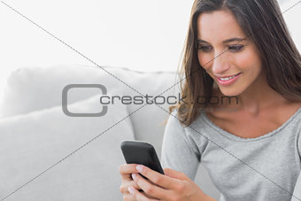 Woman text messaging while she is sat on a couch