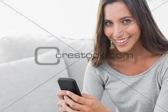 Woman texting while she is sat on a couch
