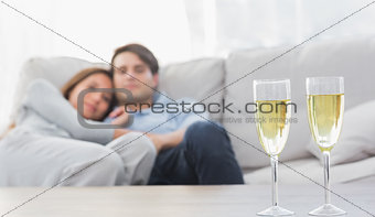Couple relaxing on a couch with flutes of champagne