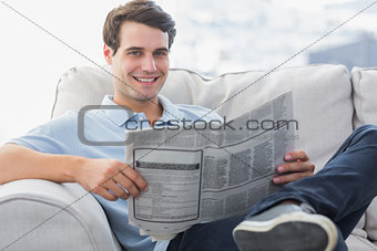 Man reading a newspaper sat on a couch
