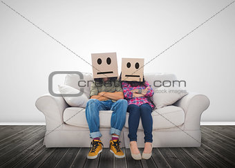 Couple sitting on couch with cardboard boxes over their head