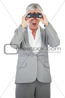 Astonished businesswoman looking at something through binoculars