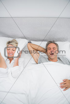 Woman blocking her ears because of partners snoring