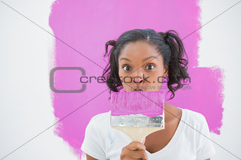 Happy woman making funny face behind paintbrush