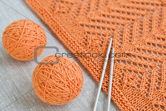 Orange balls, knitted pattern and knitting needles
