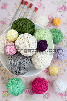 A lot of bright balls of knitting on the background of a pink flower