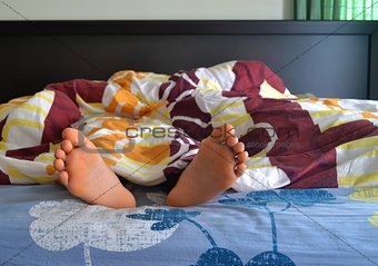 Feet under blanket in bedroom