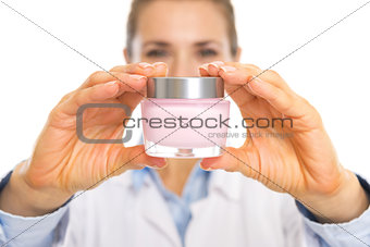 Closeup on cream bottle in hand of cosmetologist