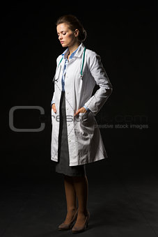 Full length portrait of thoughtful doctor woman isolated on blac