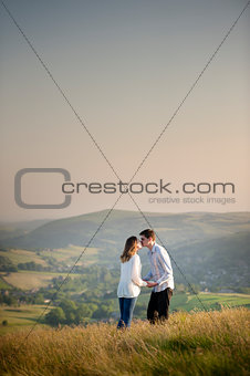 young couple kissing on a hill