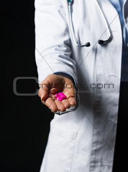 Closeup on pills in hand of doctor woman isolated on black