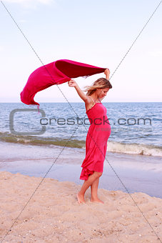 Pregnant woman with a scarf on the beach