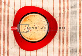 red coffee cup on striped tablecloth