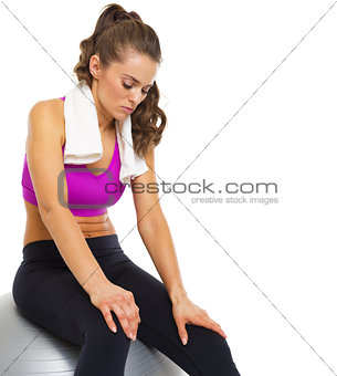 Tired young woman sitting on fitness ball