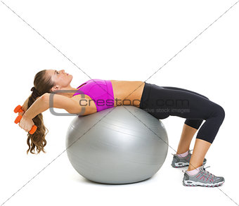 Fitness young woman making exercise with dumbbells on fitness ba