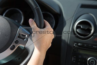 Hand on the steering wheel of a car